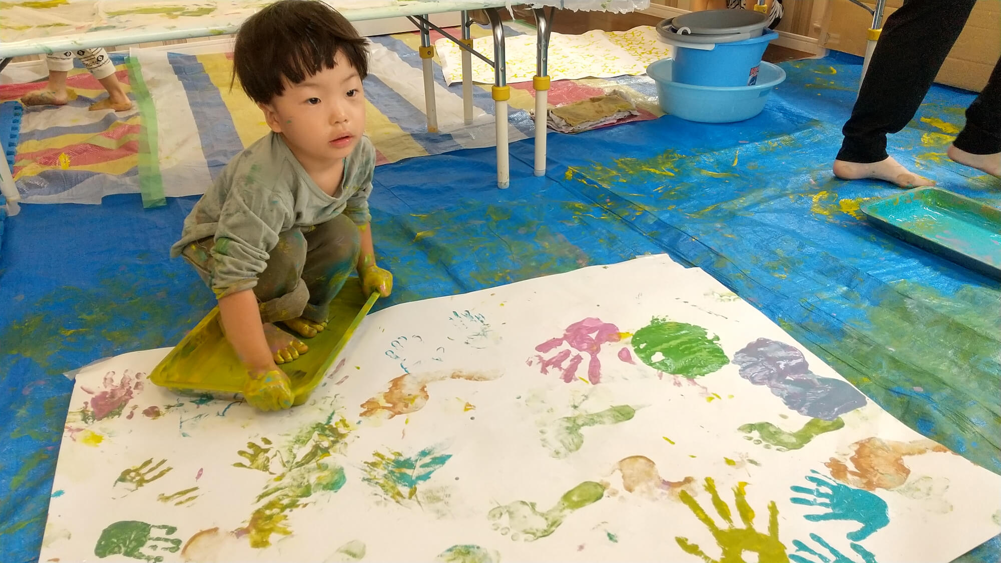 足を絵の具の中に入れ、感触を楽しむ子ども