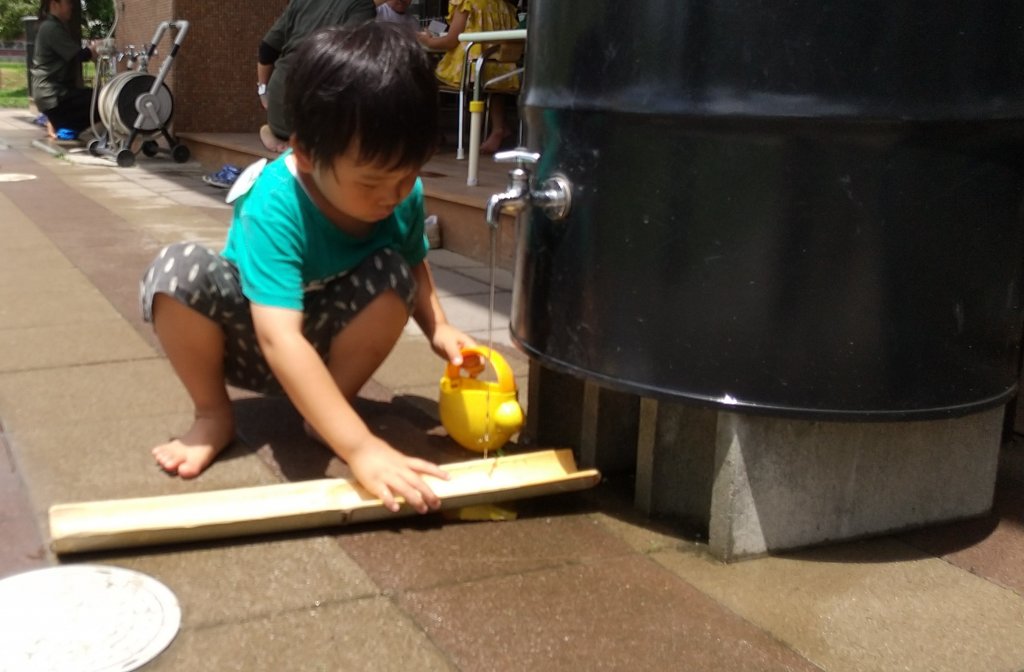 水道の下に竹を置く子ども