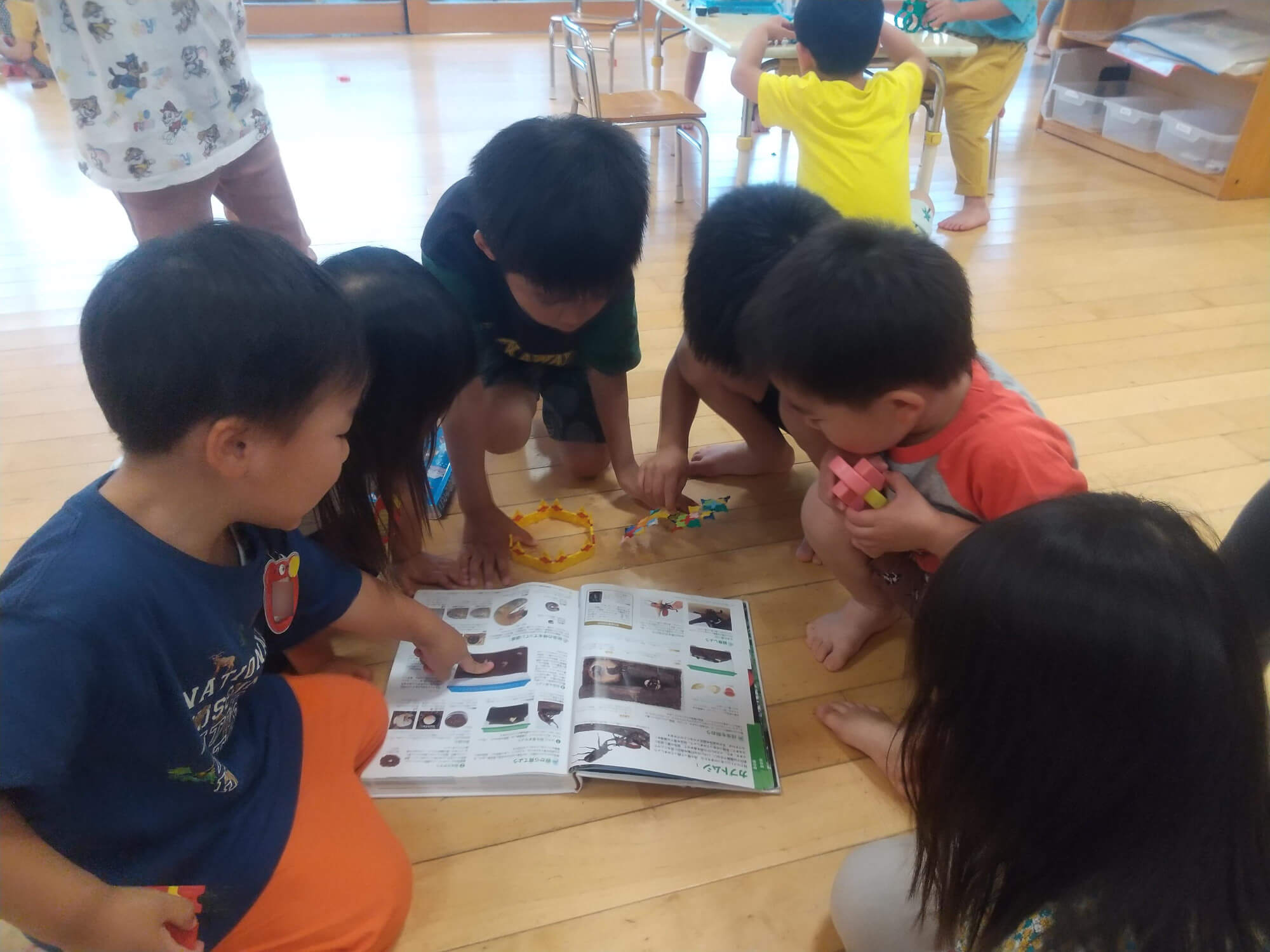 カブトムシの成長を図鑑で調べる子どもたち
