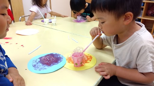 絵の具にストローで息を吹いてあじさいを描く子どもたち