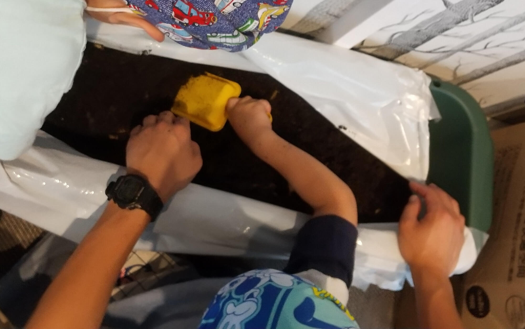コンポストにジャガイモの皮を混ぜる子ども