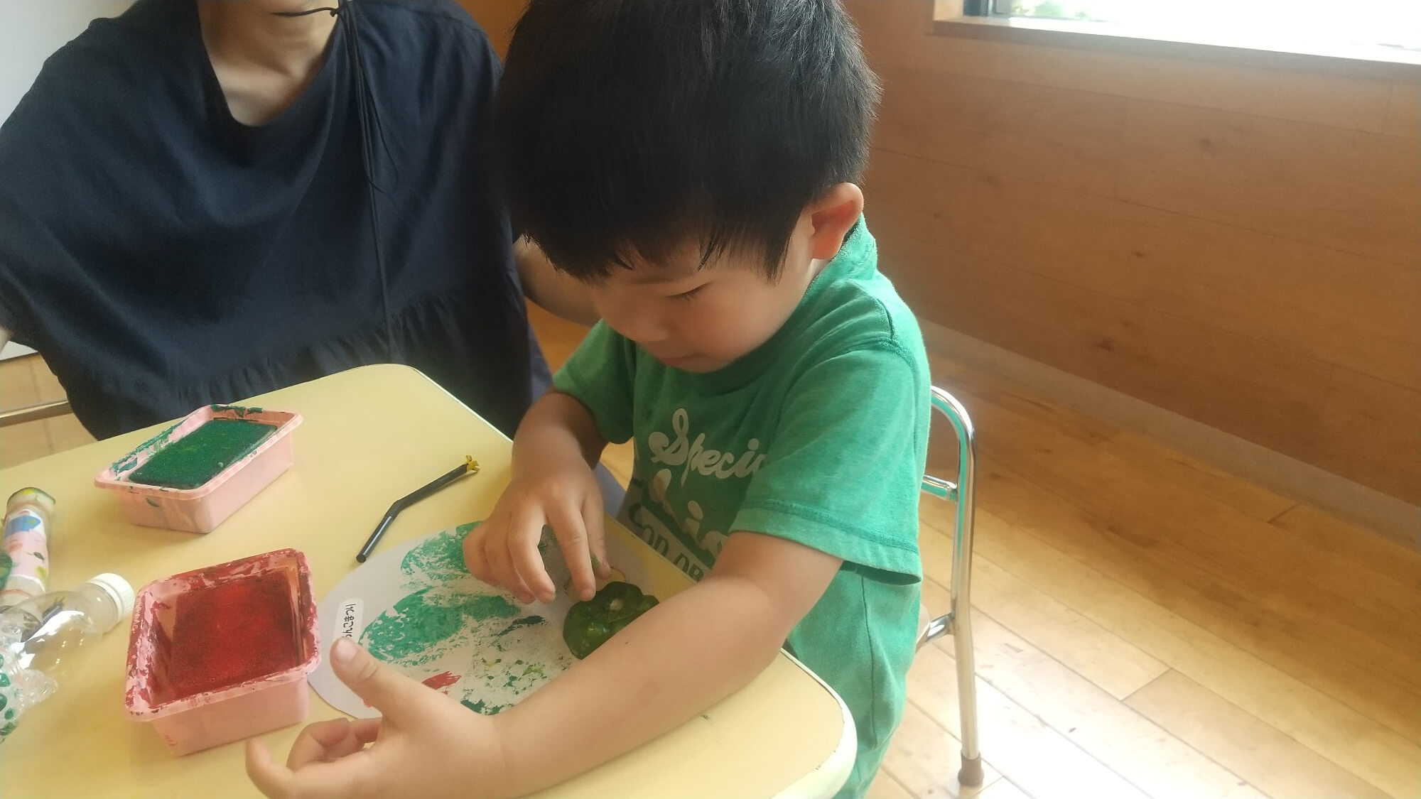 野菜スタンプでうちわに模様をつける子ども