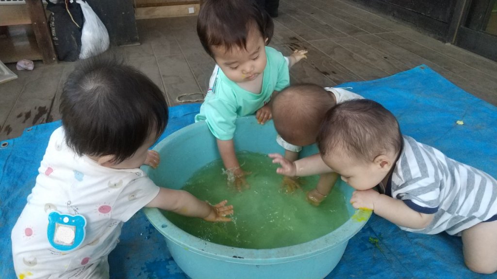 たらいで水遊びをする乳児