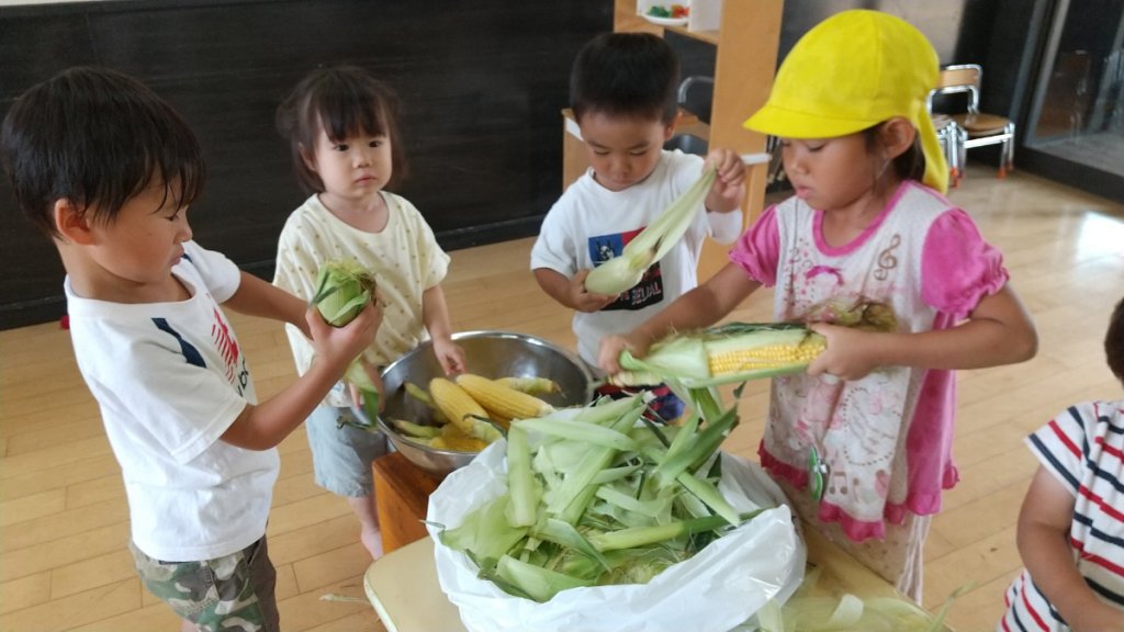 とうもろこしの皮をむく子どもたち