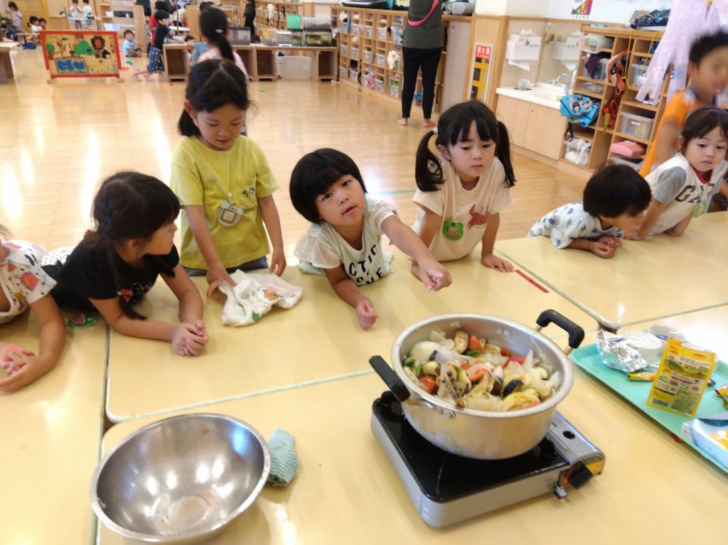 野菜を煮込む鍋をのぞく子どもたち