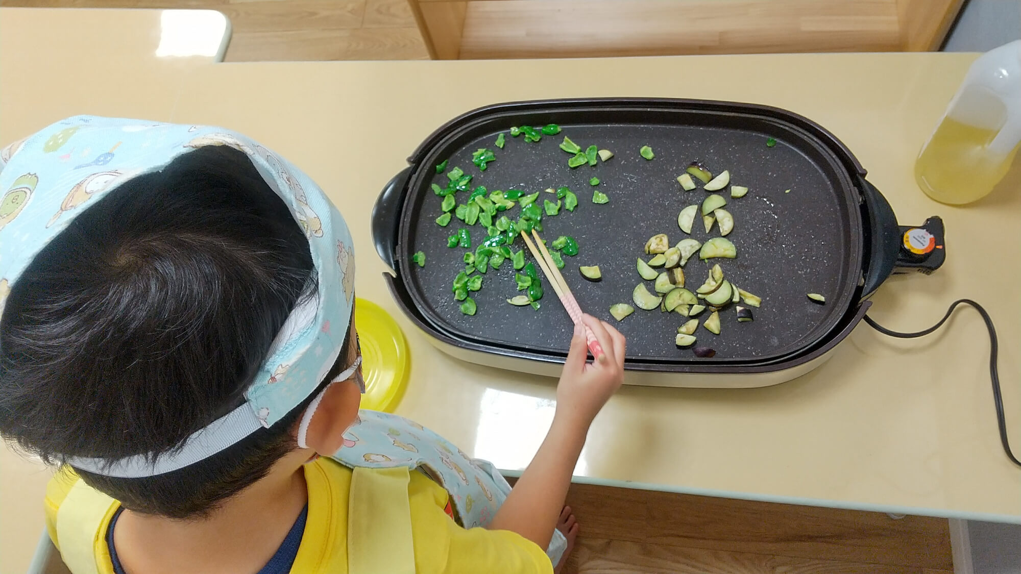 ホットプレートで夏野菜を焼く子ども