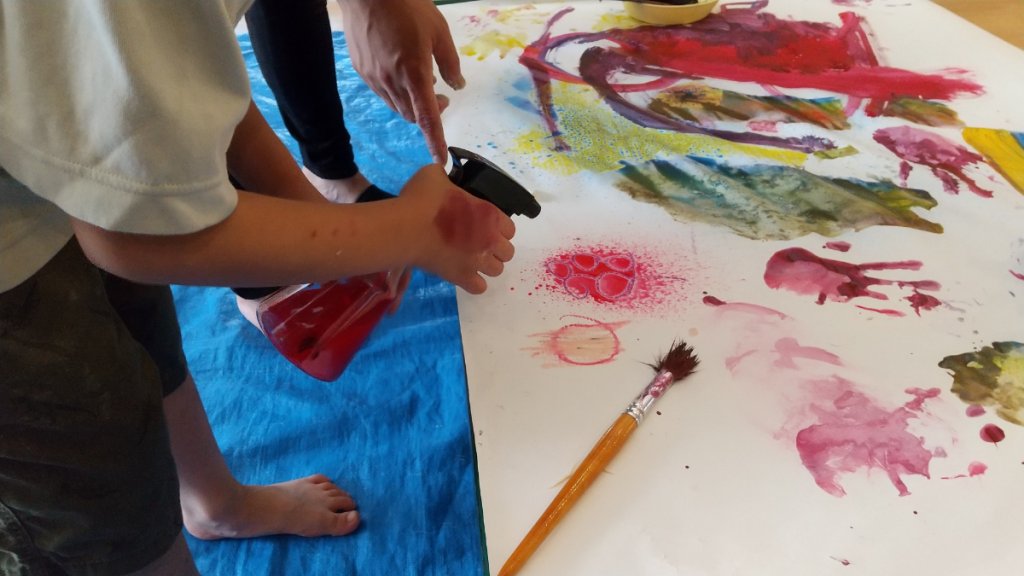 霧吹きで絵の具に水をかける子ども