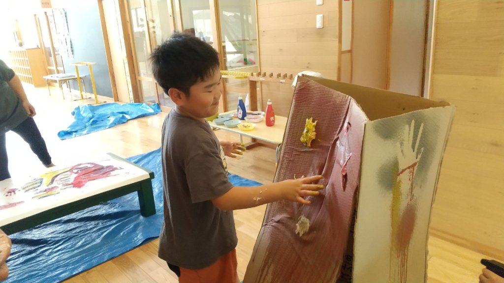 小麦粉粘土をダンボールに貼り付ける子ども