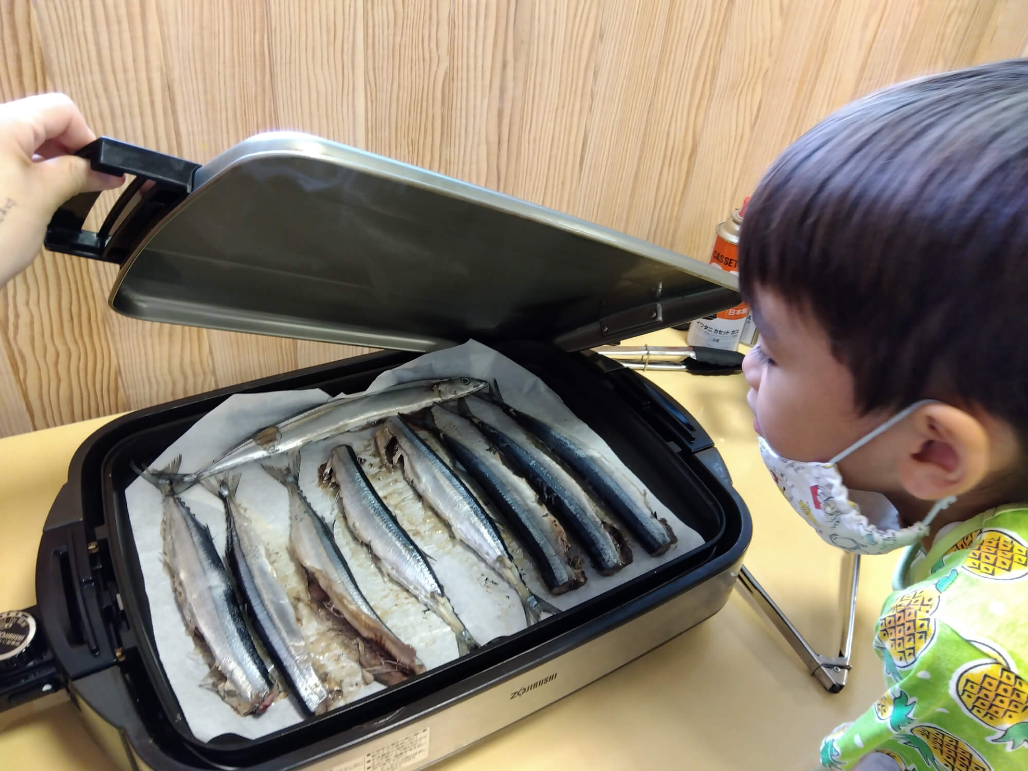 焼けるサンマを眺める子ども