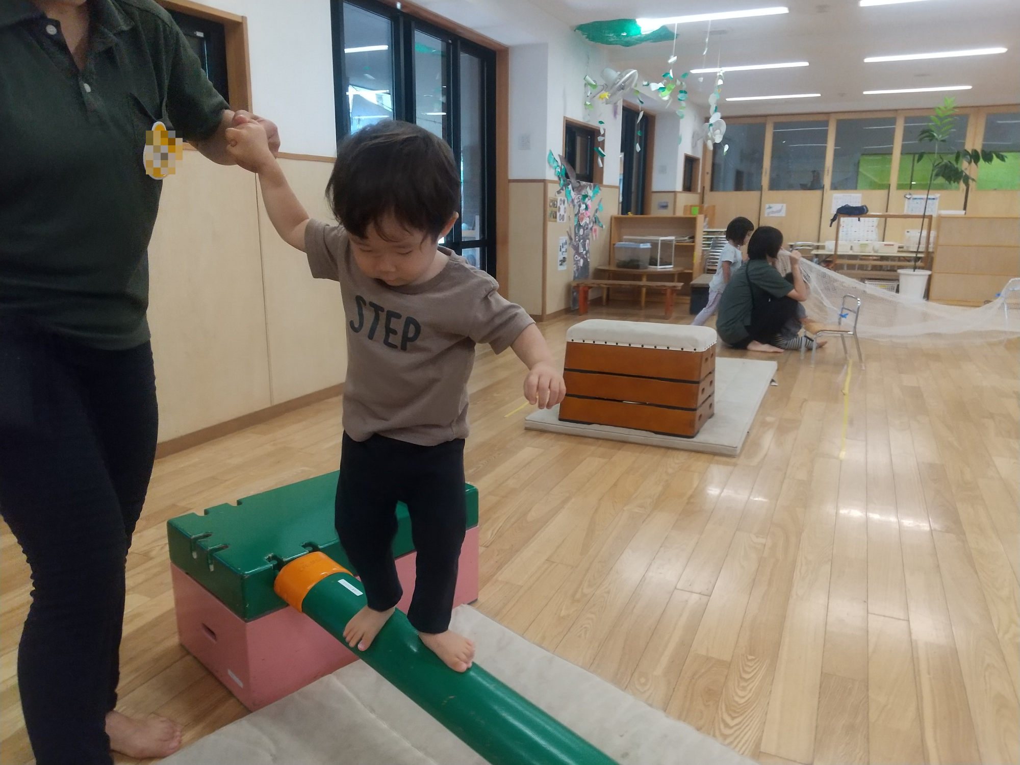 巧技台をスタッフの助けで渡る子ども