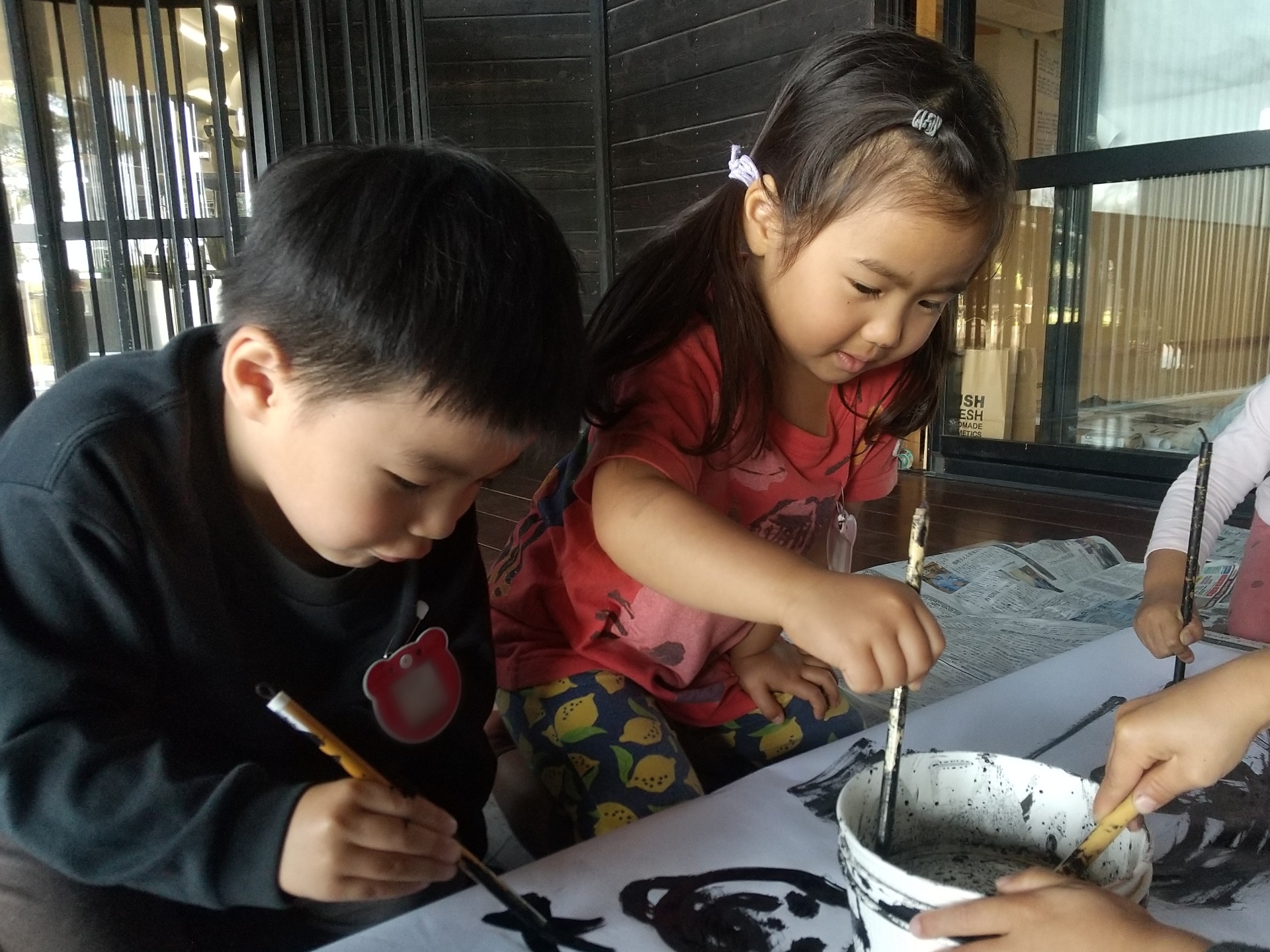 筆を墨につける子どもたち