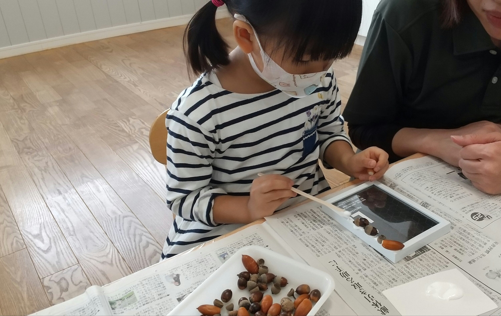 フォトフレームをどんぐりで飾る子ども