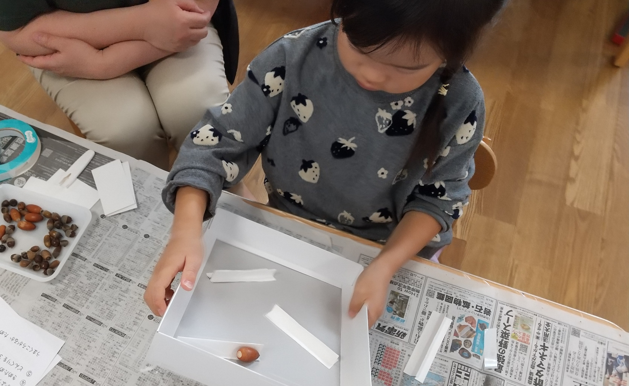 迷路を傾けてどんぐりを転がす子ども