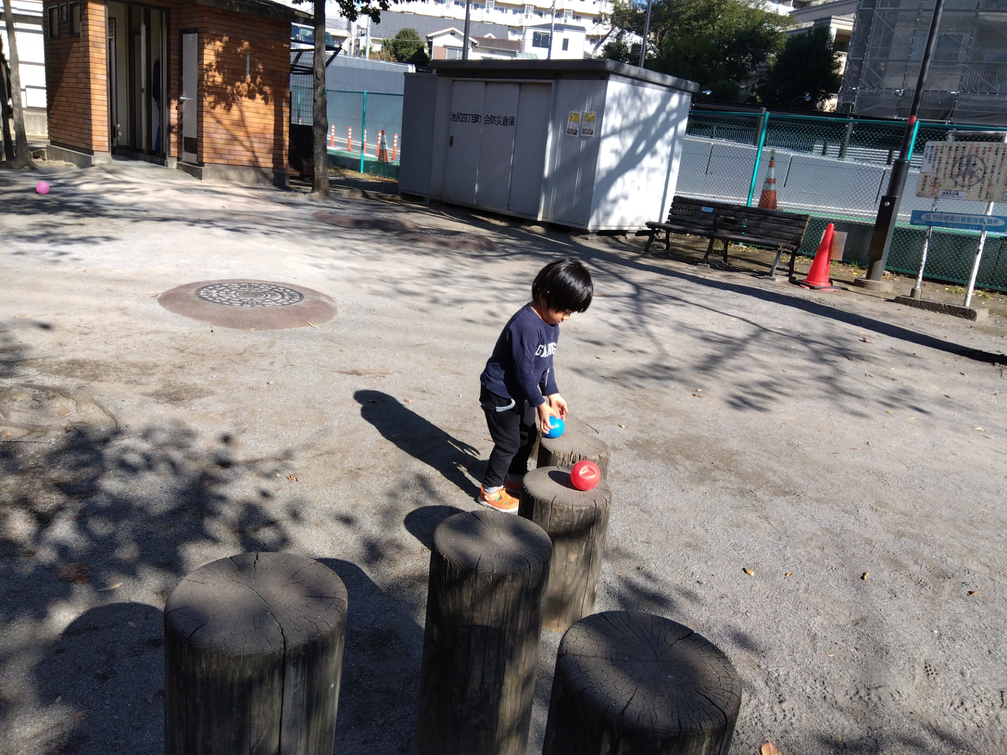 丸太にボールを乗せる子ども