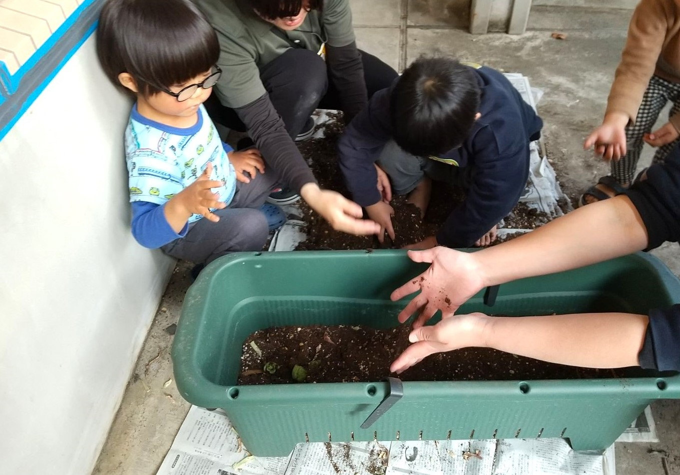 プランターに土を入れる子どもたち