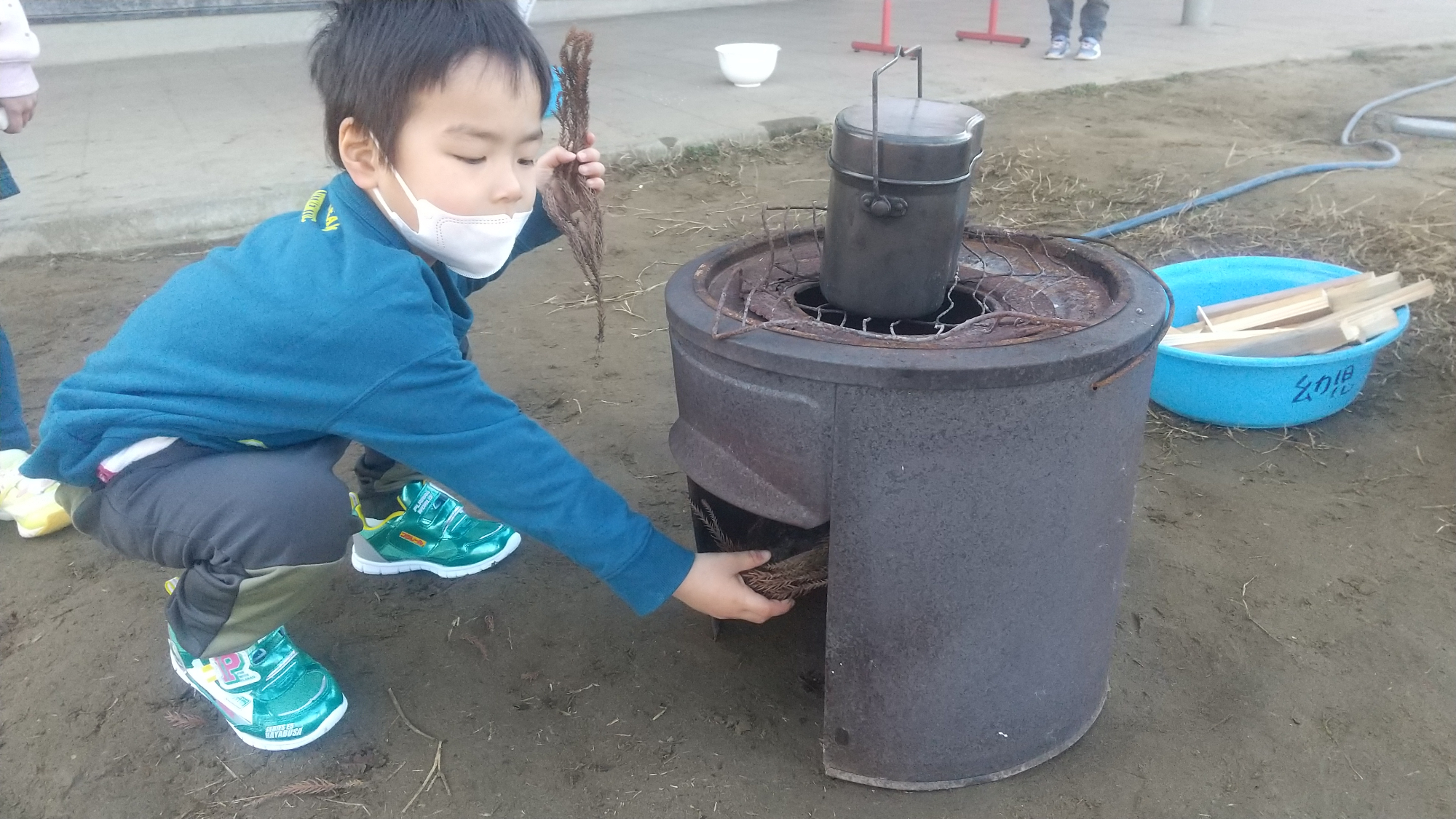 釜に枯れ葉を入れる子ども