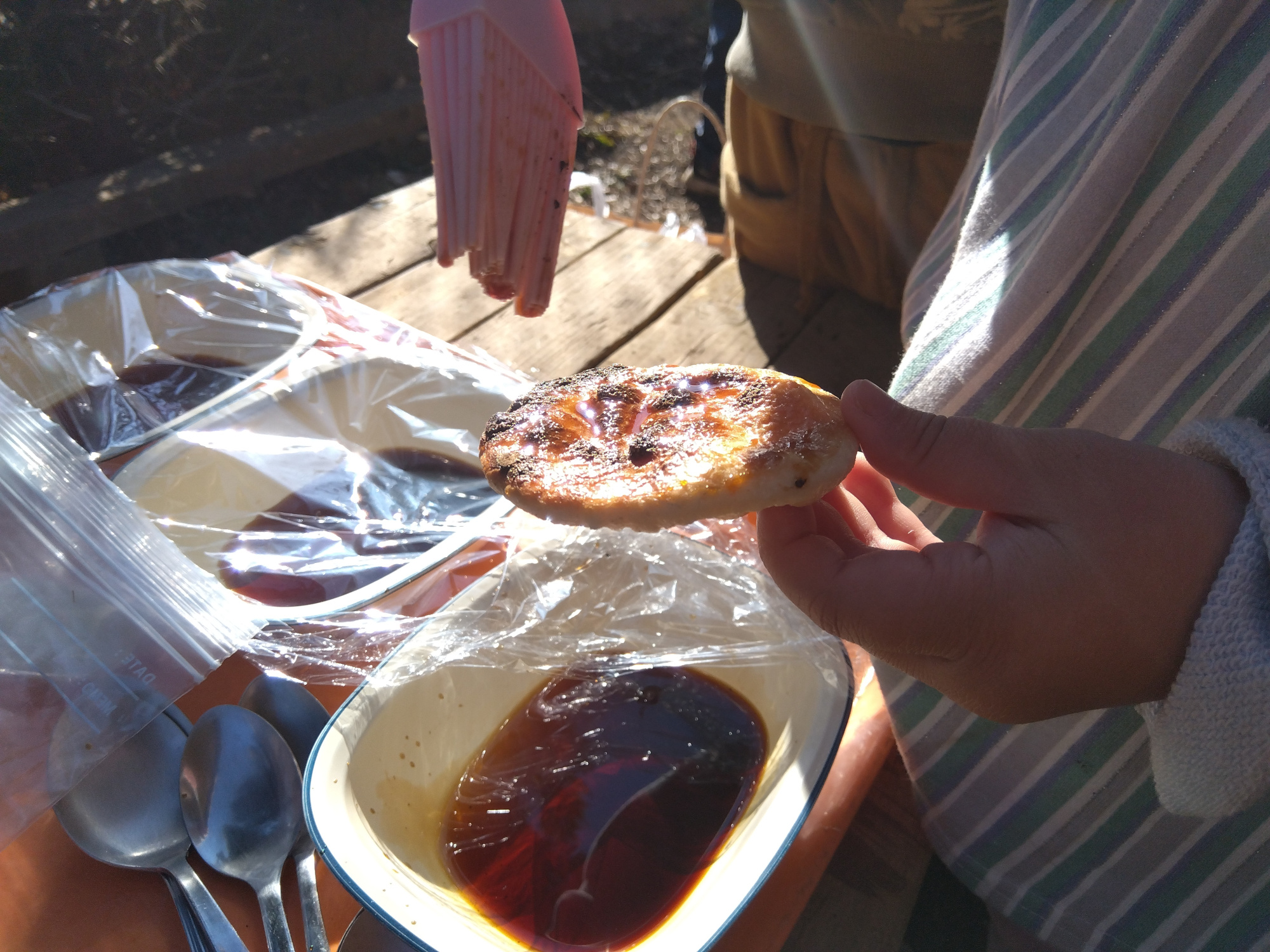 せんべいにはけで醤油だれをつける子ども