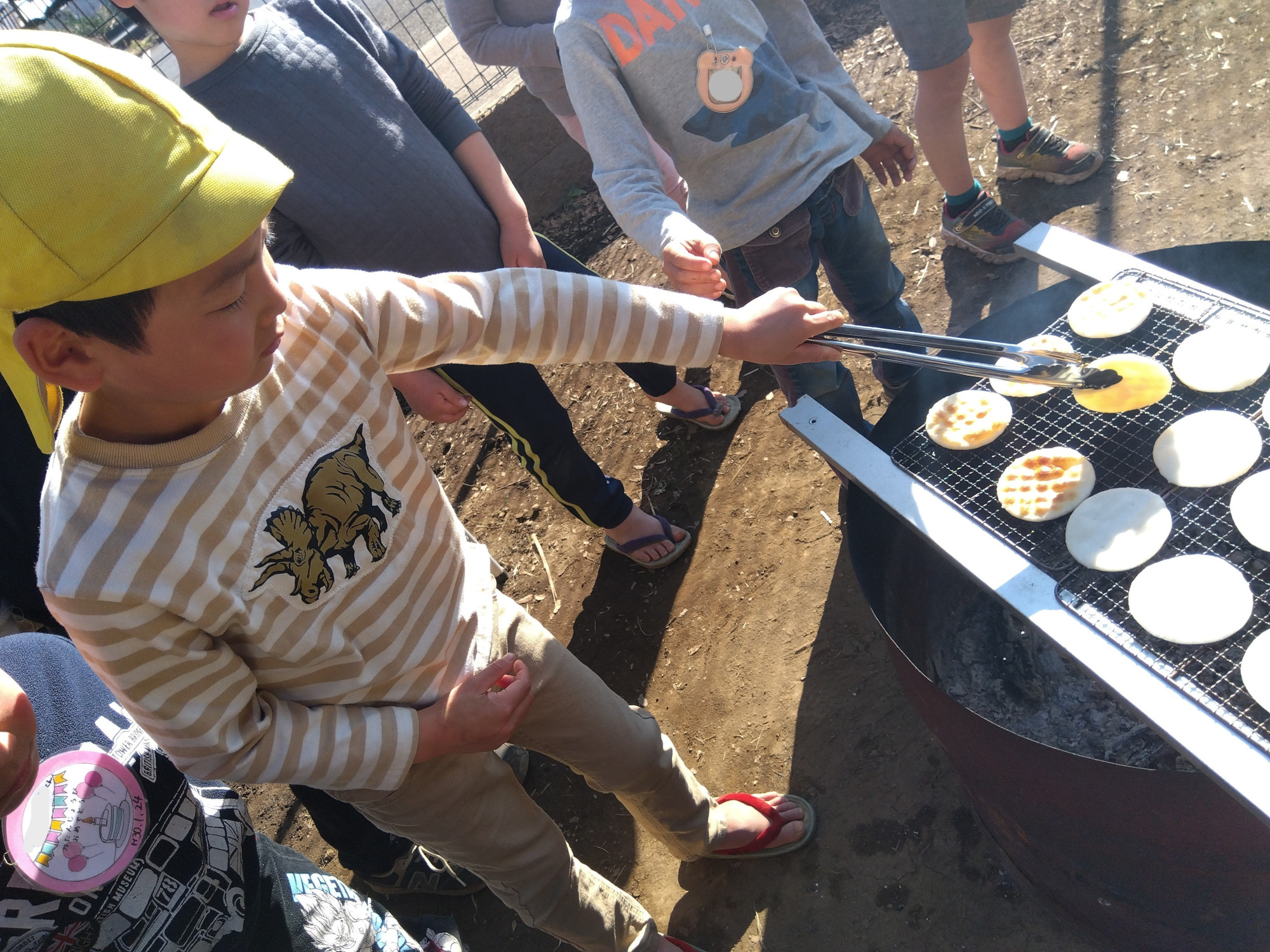 トングを使ってせんべいをひっくり返す子ども