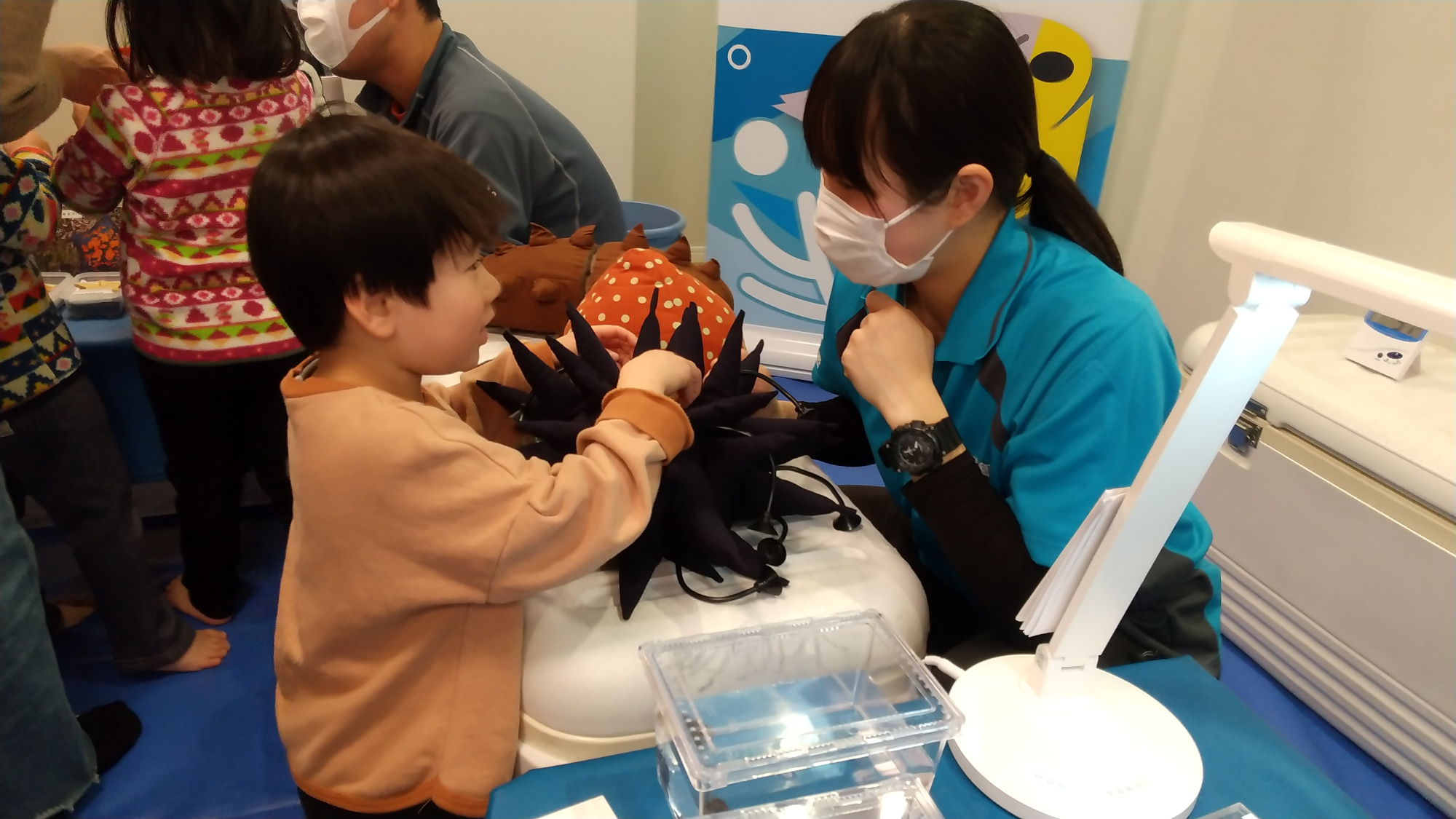 ウニのぬいぐるみを見ながらスタッフに質問する子ども