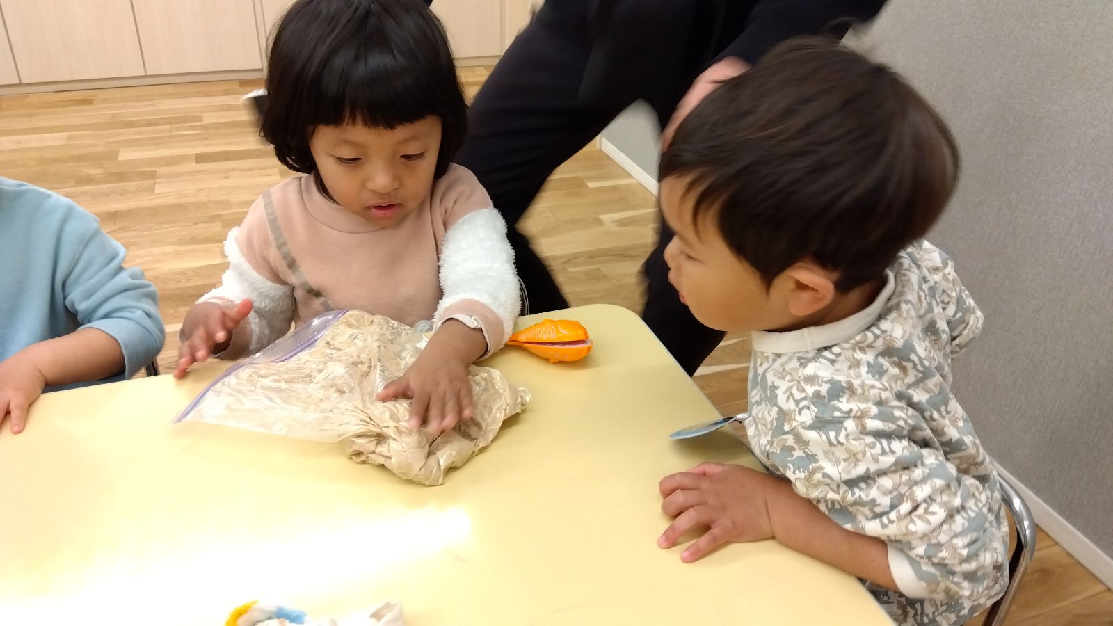 ポリ袋の上からピザ生地をこねる子どもたち