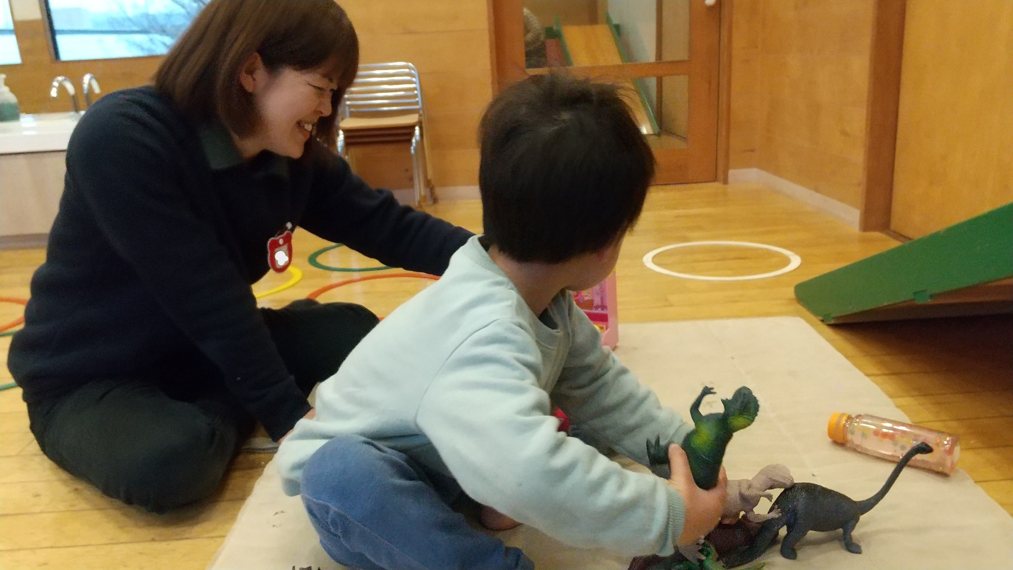 スタッフと一緒に人形で遊ぶ子ども