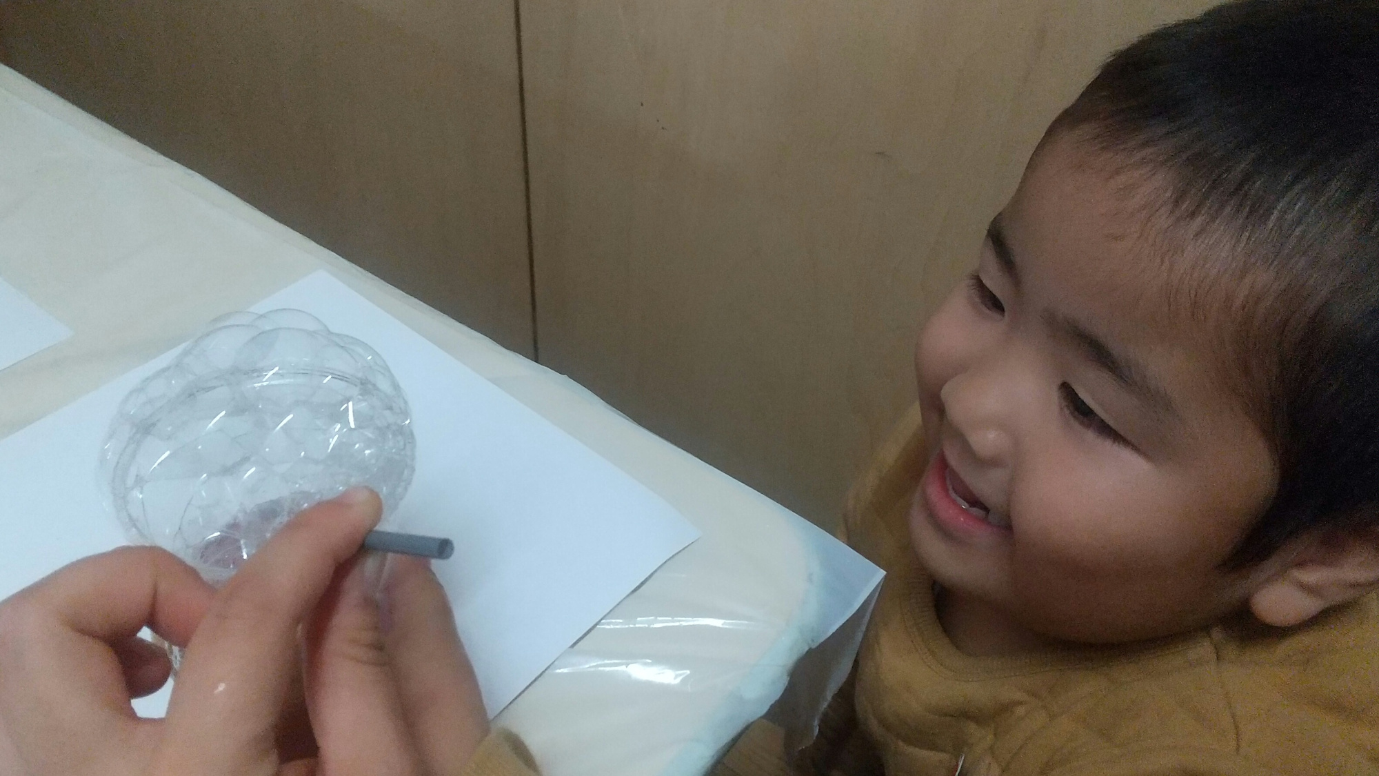 ストローを使って泡を作る子ども
