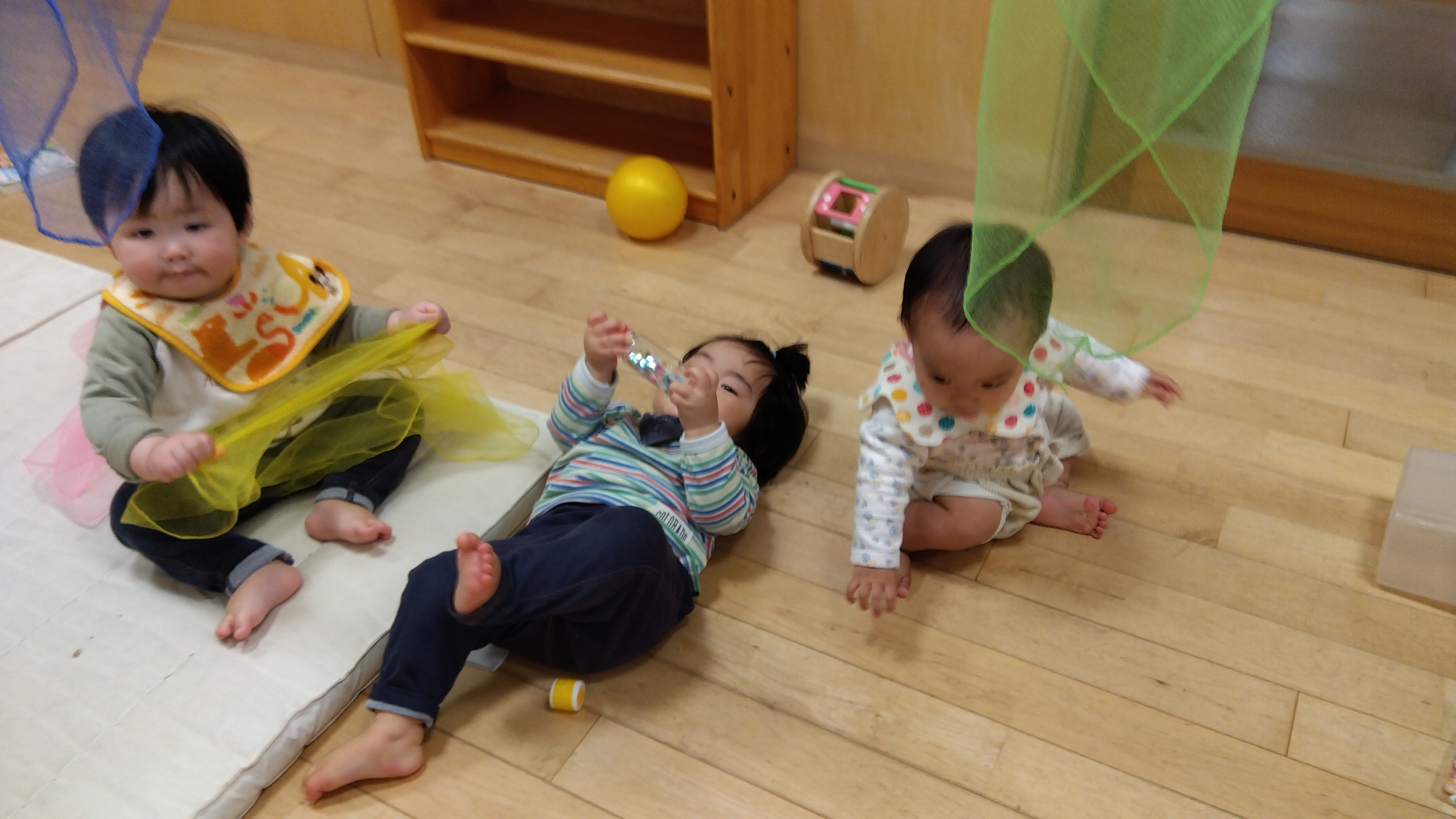 保育室でカラーシフォン布に触れて遊ぶ子どもたち