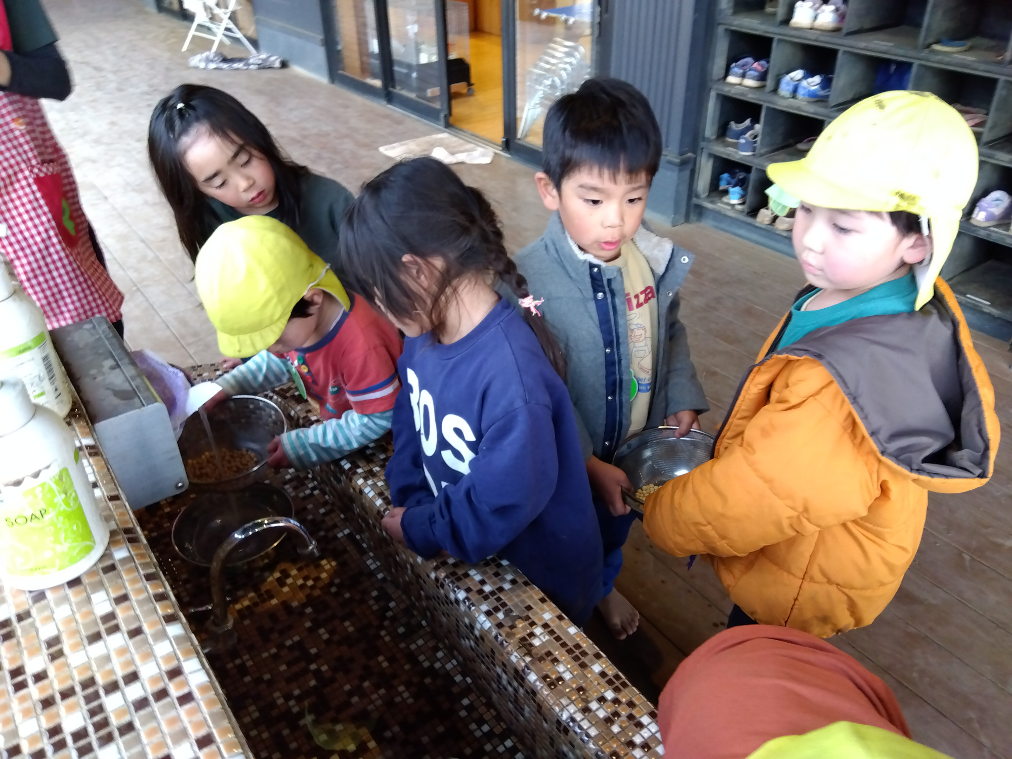 大豆が入ったボールに水を入れて浸す子どもたち