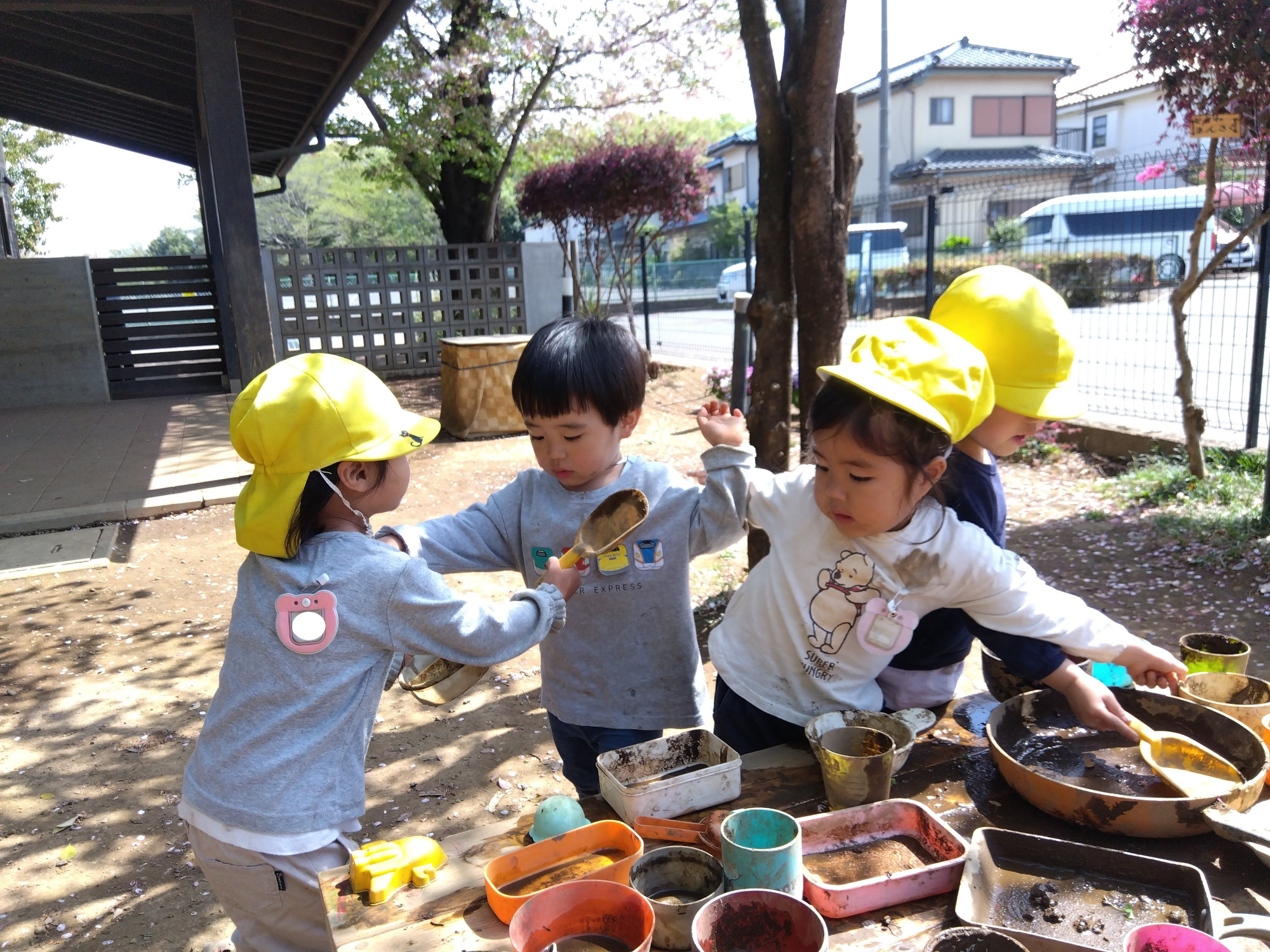 園庭でおままごとをしながら物の取り合いをする子どもたち