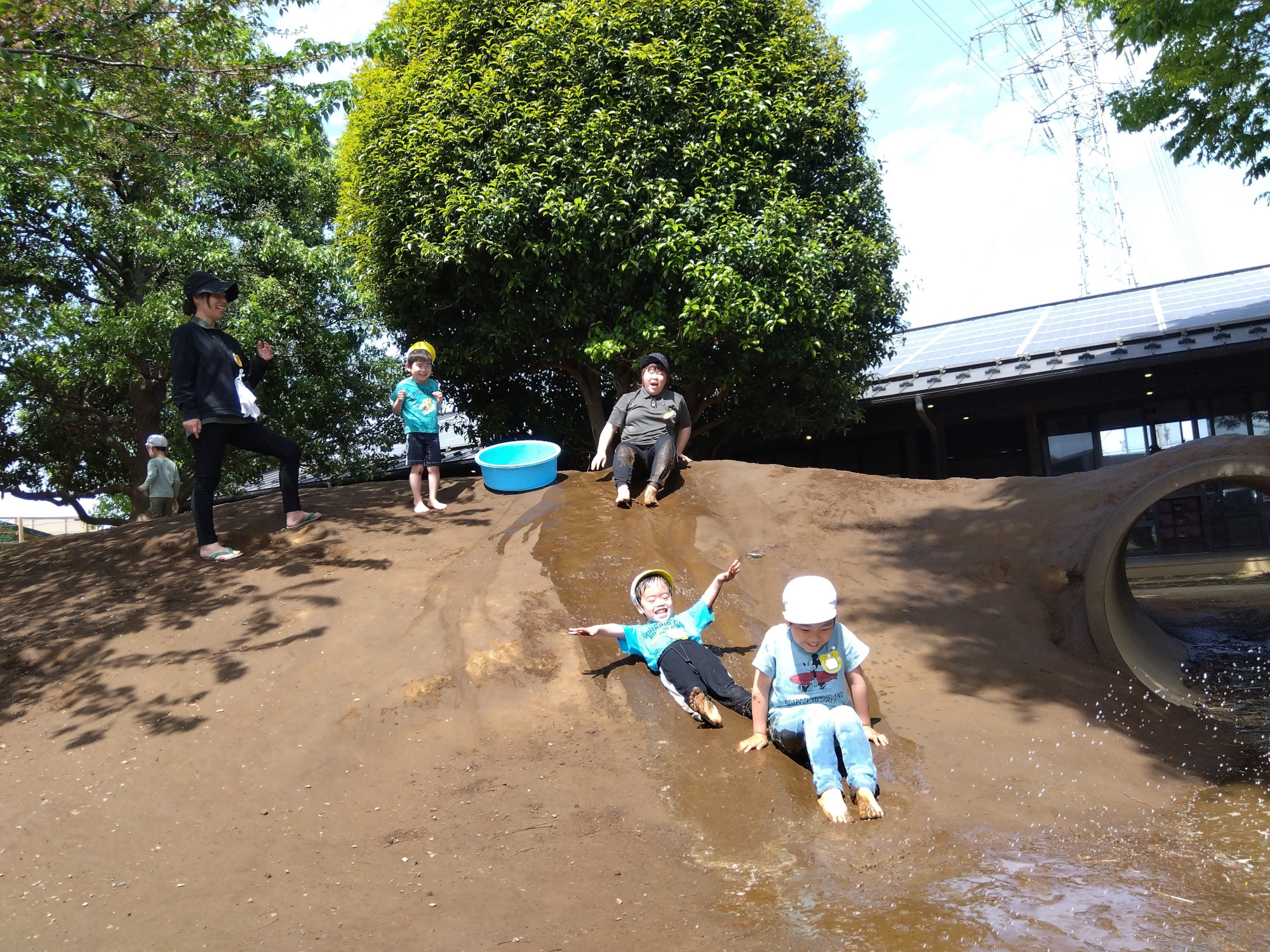 築山に水を流して滑り降りる子どもたち
