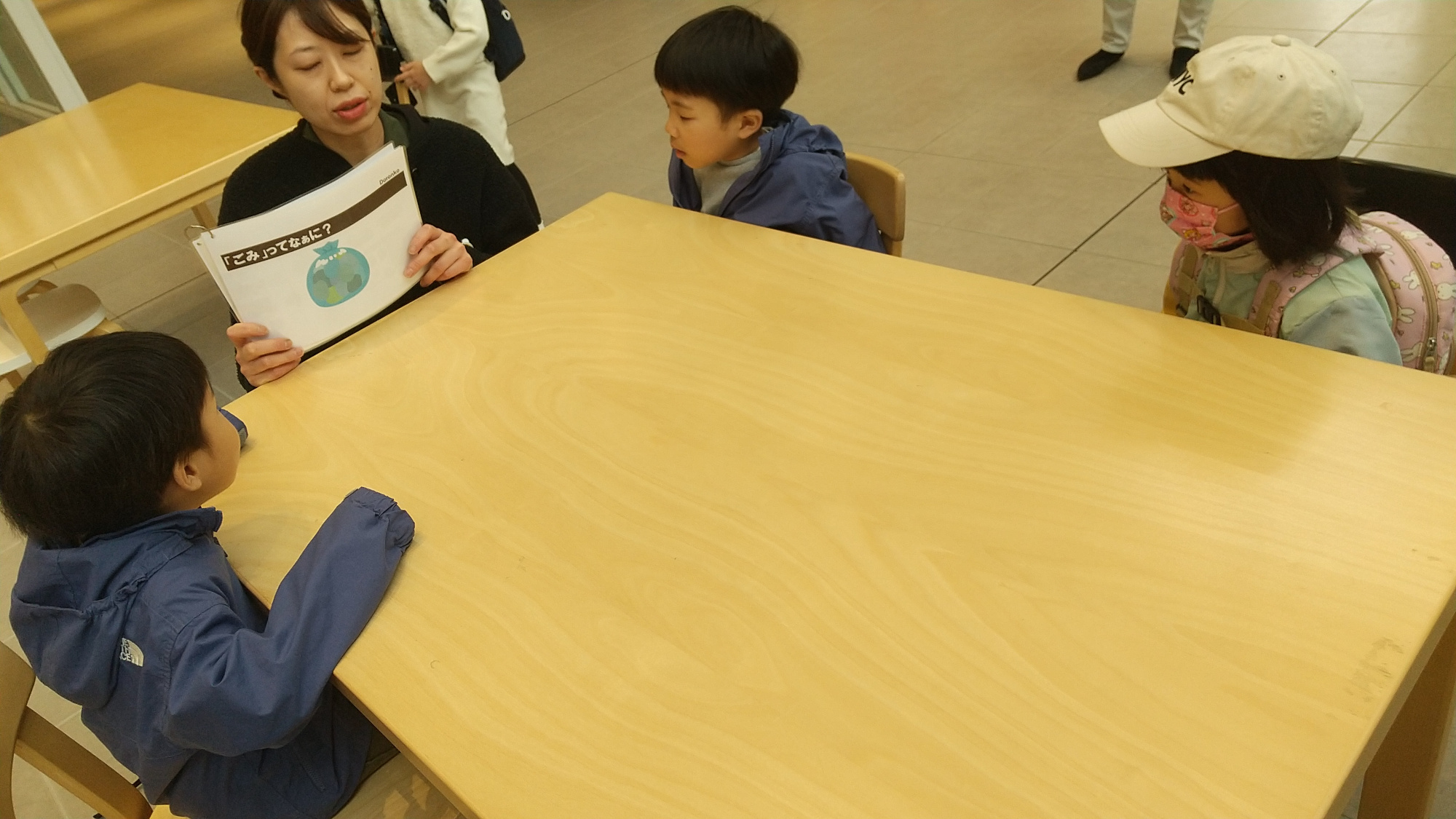 スタッフが子どもたちに絵を見せながらごみ処理場について説明する様子