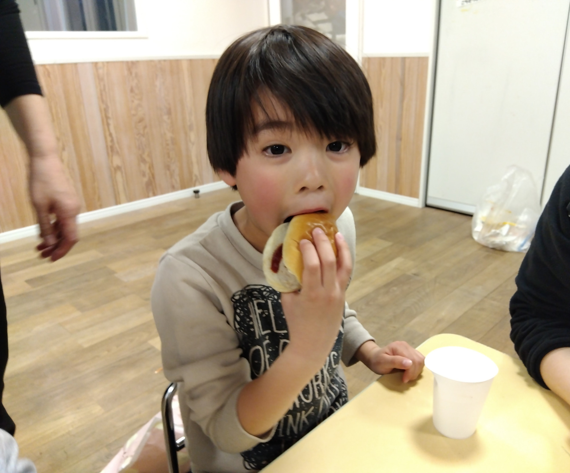 作ったホットドックを食べる子ども