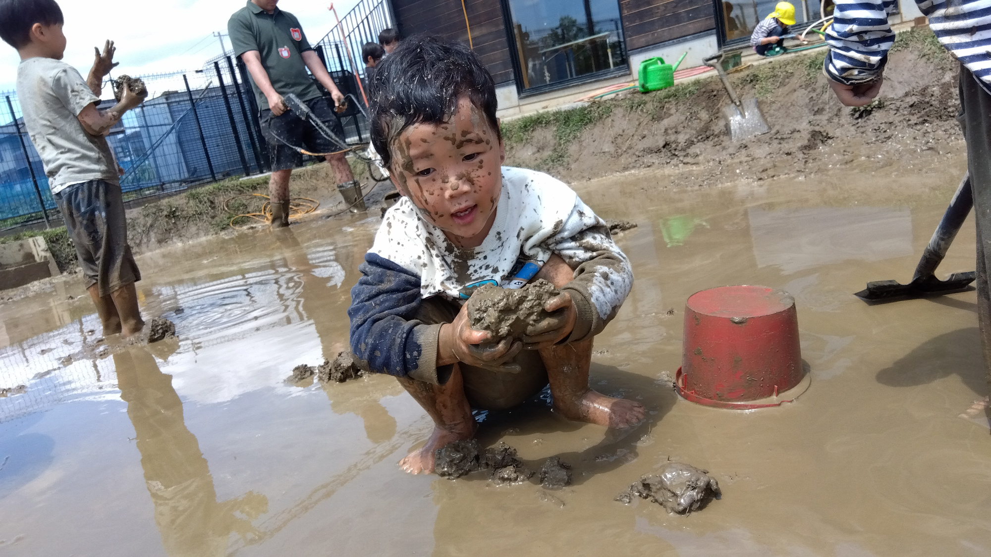 園庭の田んぼで泥遊びをする子どもたち