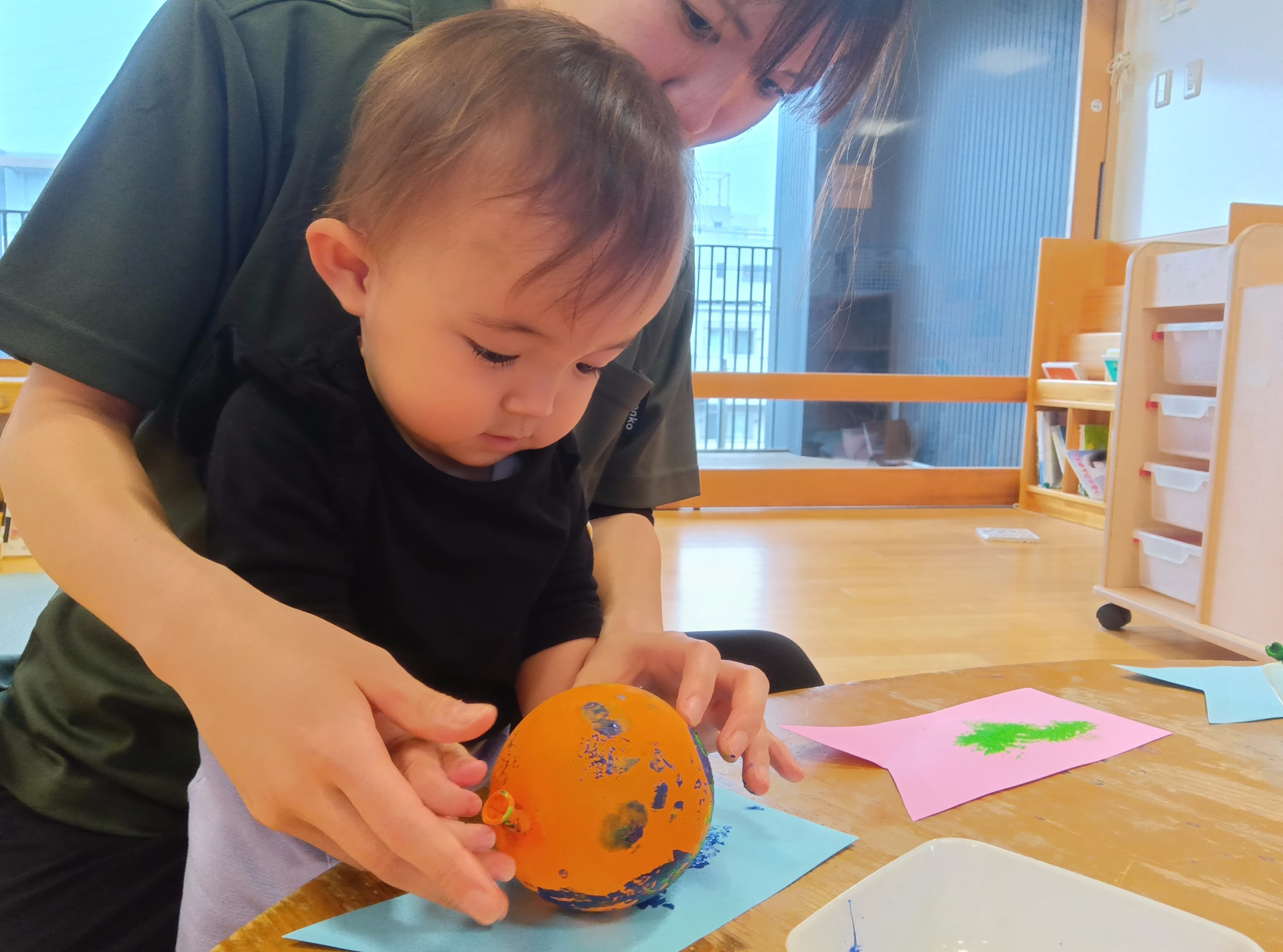 風船を使って画用紙で作った鯉のぼりに模様をつける様子