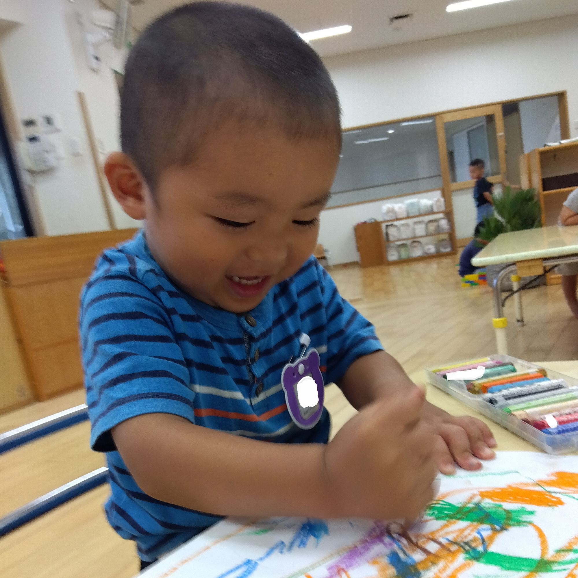 クレヨンで画用紙に絵を描く子ども