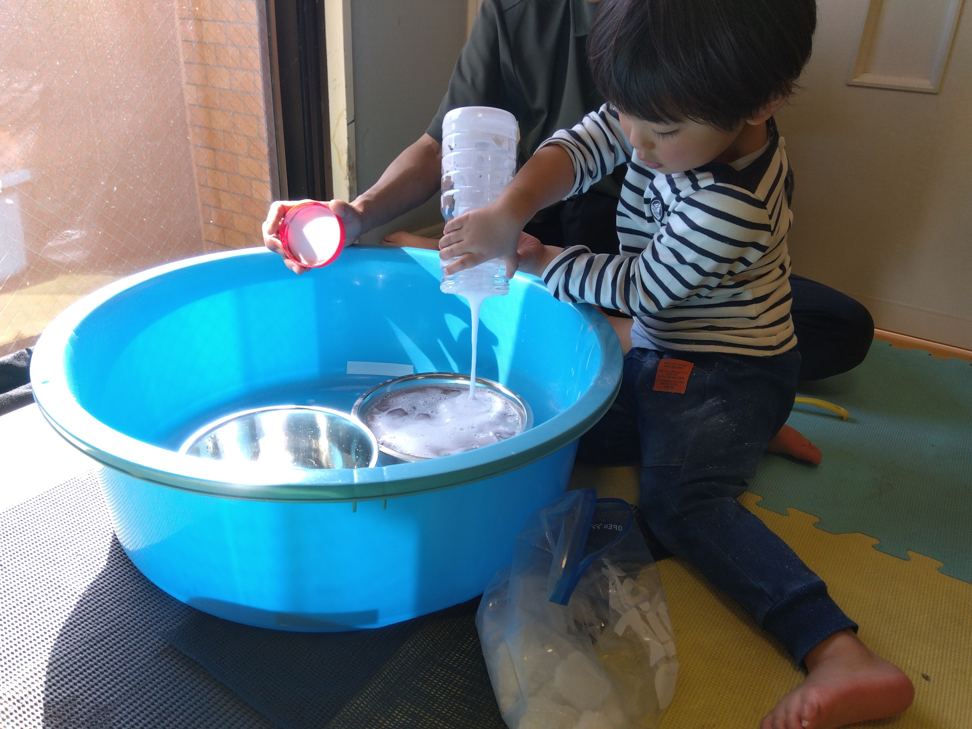 たらいにボトルの中の泡を注ぐ子ども