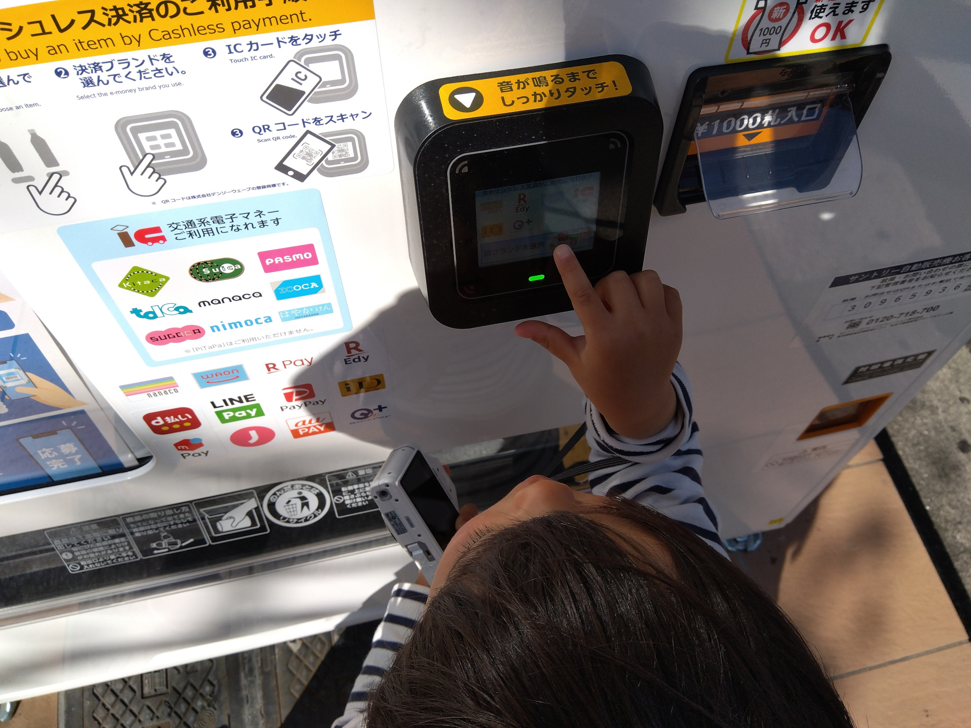 自動販売機のICタッチ部分に触れる子ども