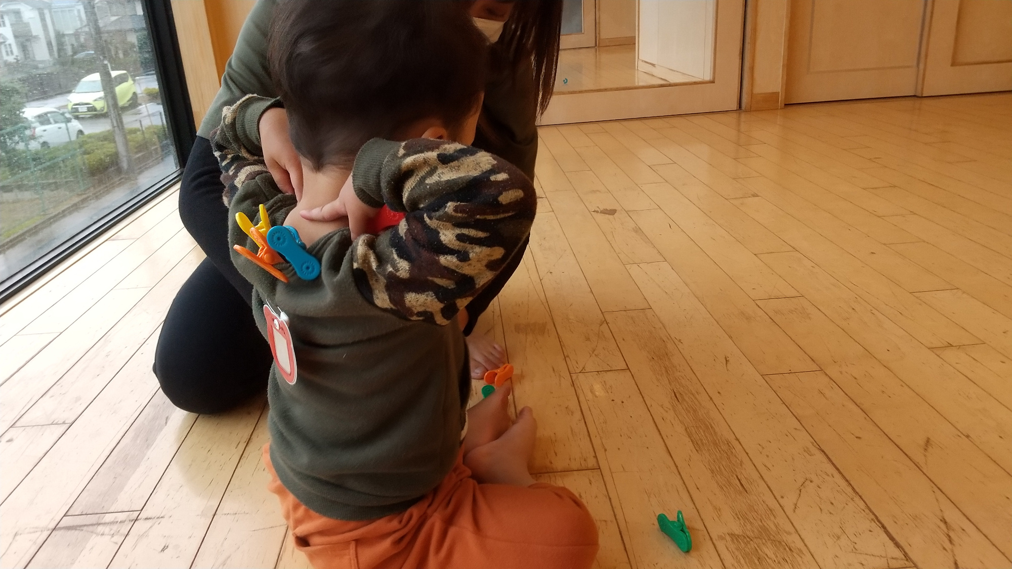 服についたクリップを取ろうとする子ども