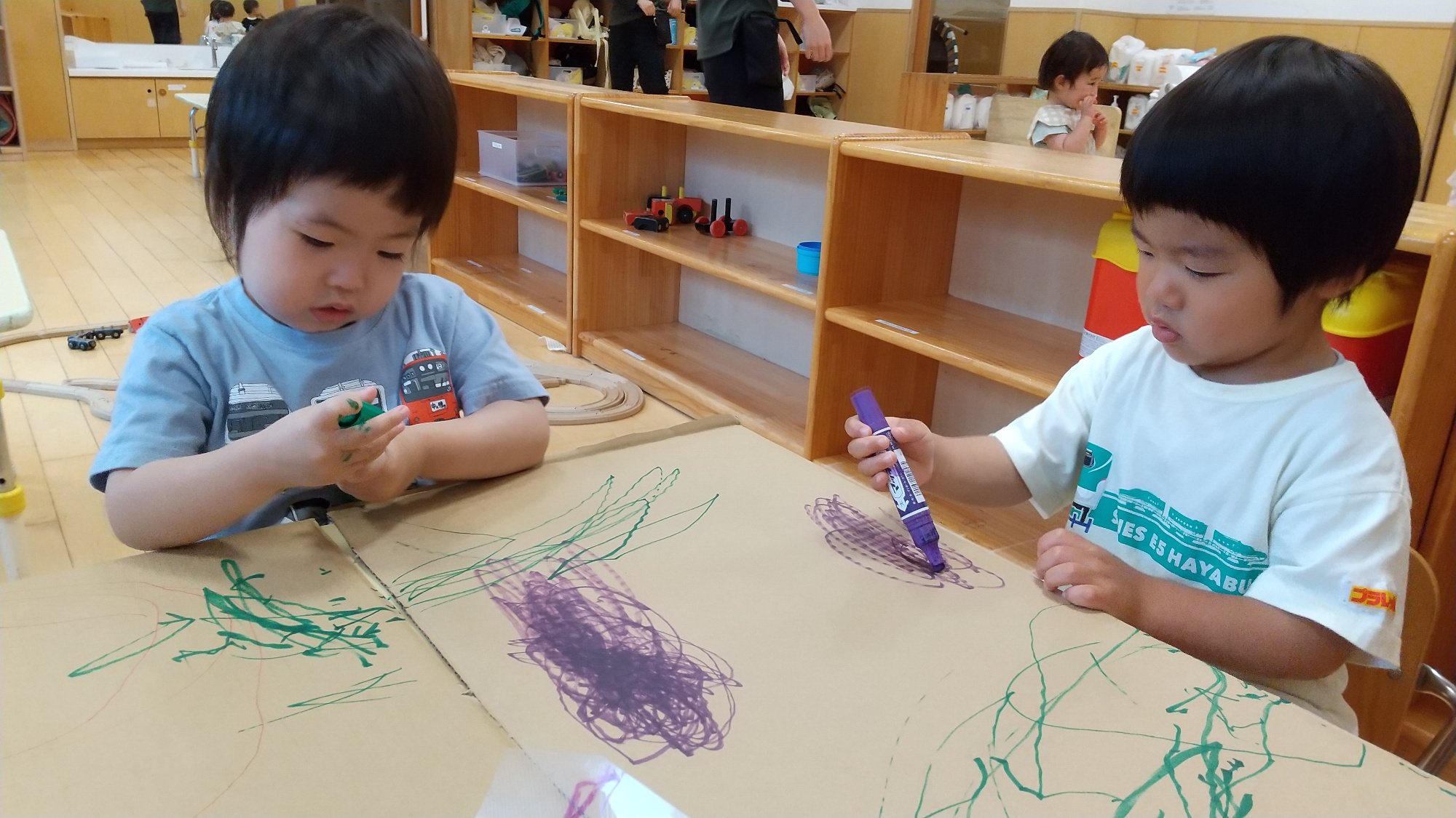 段ボールにマーカーで模様を付け、ソリを作る子どもたち