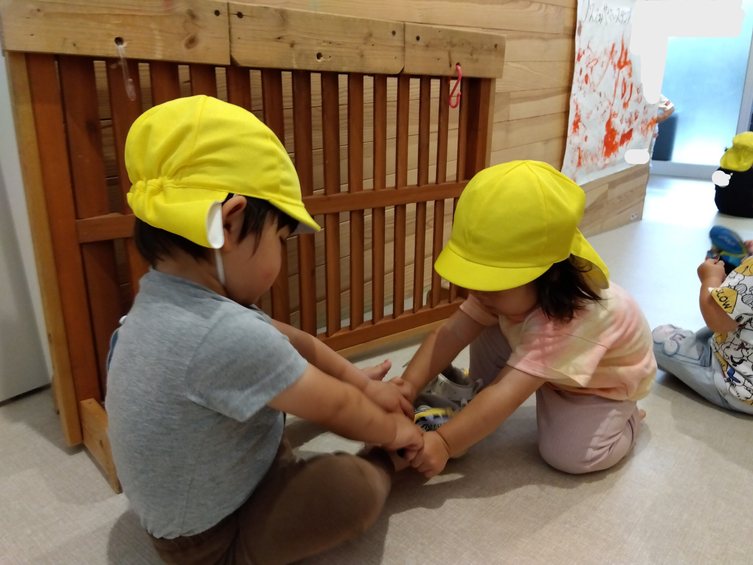 子ども同士で靴を履かせてあげる様子