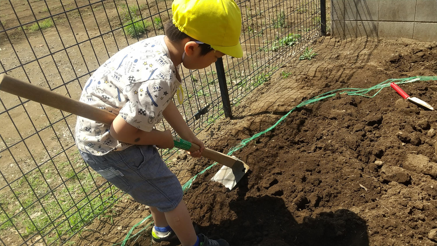 鍬を使って畑を耕す子ども