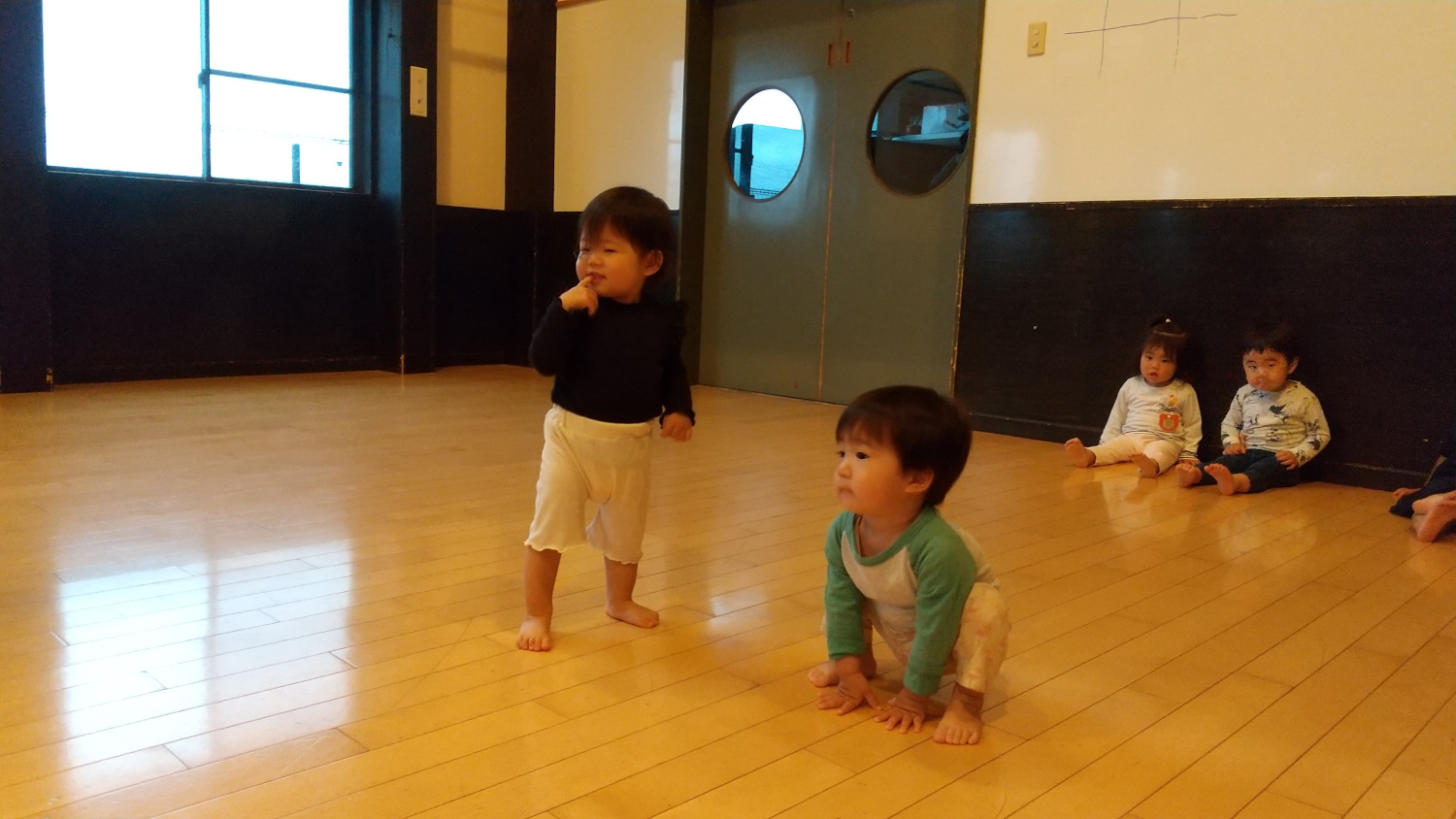リズム体操をする子どもと、後ろから眺める子どもたち