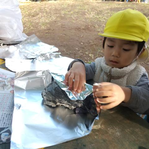 さつまいもをアルミホイルで包む子ども