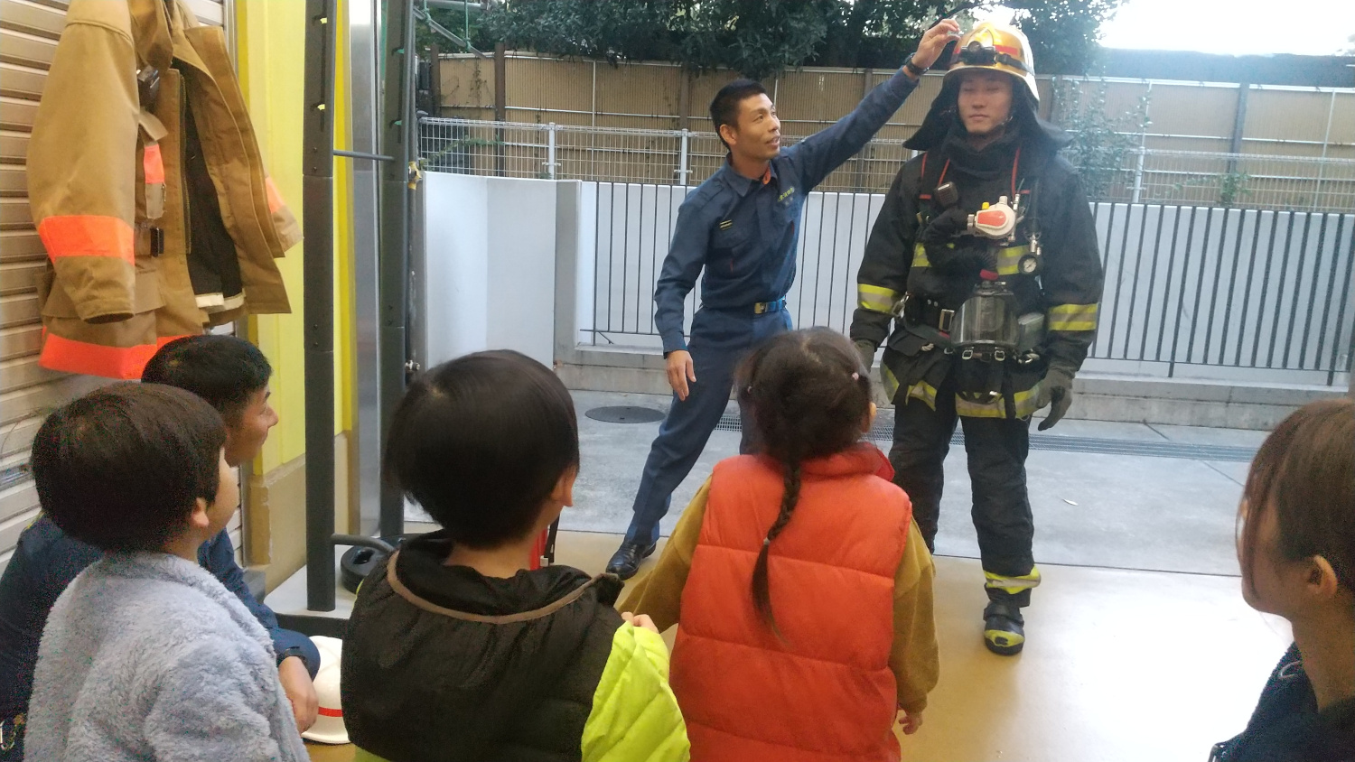 消防福を装着する様子を見る子どもたち
