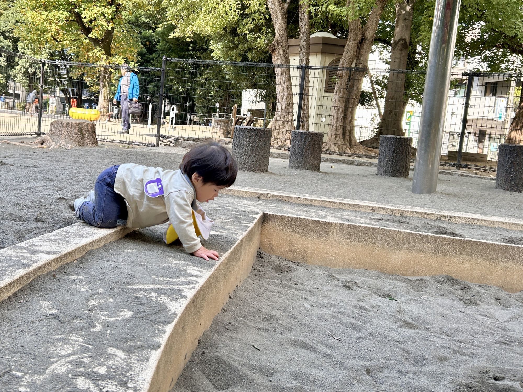 1歳児の子どもが砂場をのぞき込む
