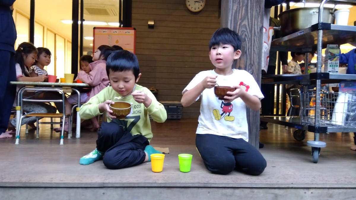 縁側で芋煮を食べる子ども