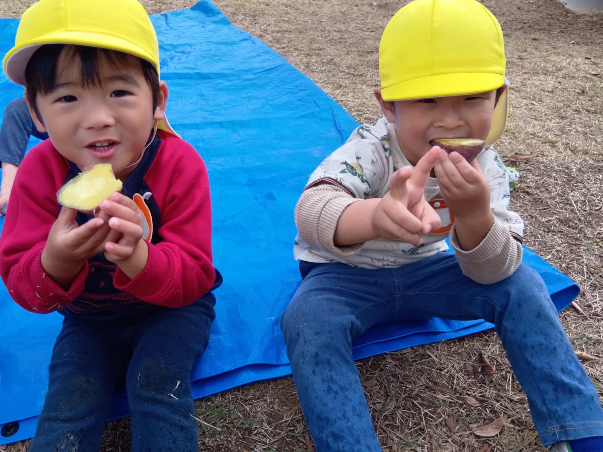 園庭で焼き芋を食べる子どもたち
