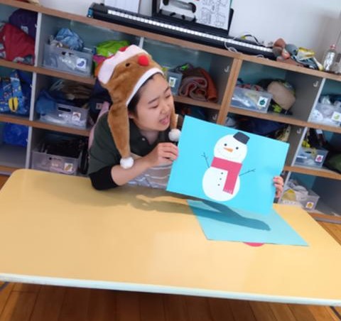 雪だるまの絵を見せるスタッフ