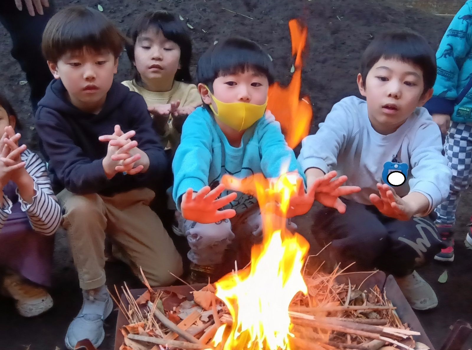 焚き火で暖をとるこどもたち