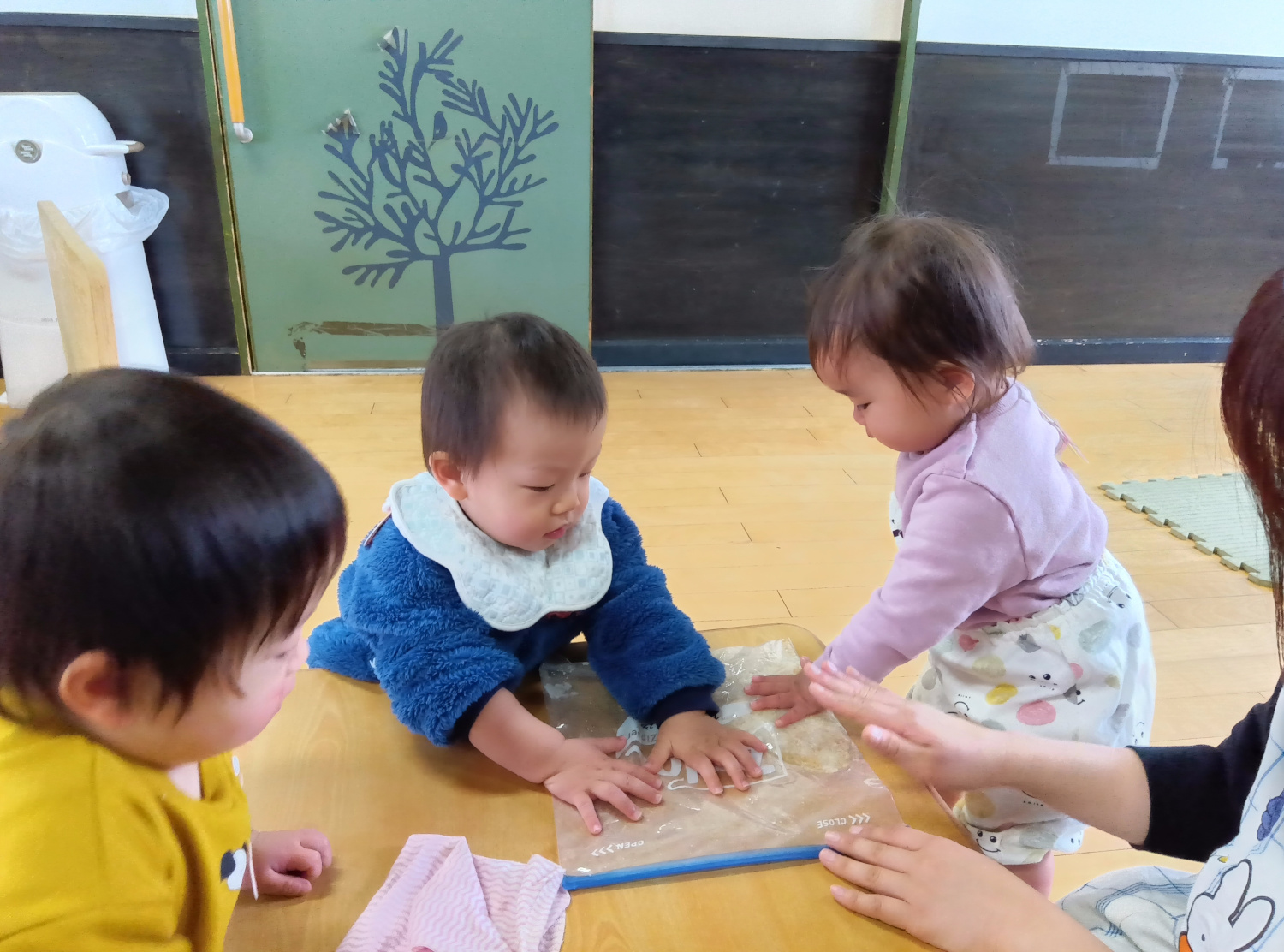 ビニール袋に入ったお米を潰す乳児たち